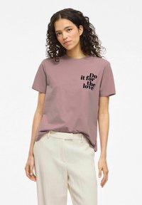 Camiseta de algodón de manga corta en color malva con cuello redondo, que presenta texto negro: "Hazlo por amor" en el lado izquierdo.