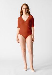 Bañador de una pieza en color óxido con escote en V profundo, mangas cortas y textura acanalada. Presenta una silueta ajustada y un diseño minimalista.