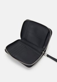 Black leather wallet with a zip closure, featuring multiple card slots and a smooth interior finish. Labeled with "Calvin Klein."