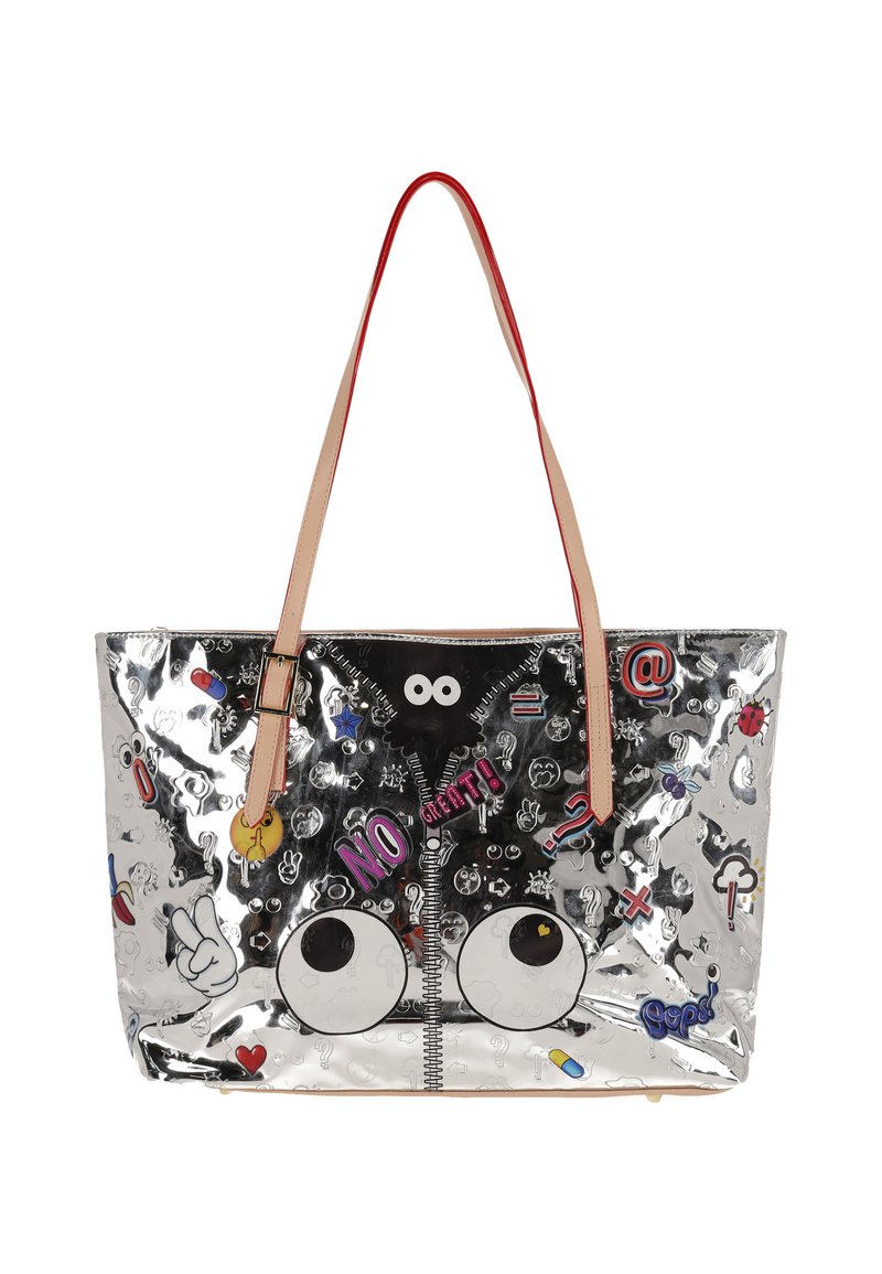 Bolso tote plateado con superficie brillante, adornado con pegatinas y gráficos coloridos, que incluyen ojos y texto, con asas beige y cierre de cremallera.
