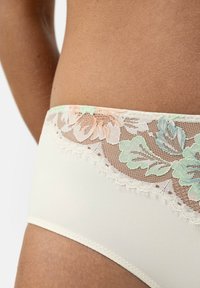 Crèmekleurige hipster string met bloemenkant in pastelroze en groen, voorzien van gegolfde randen en een gladde stofstructuur.