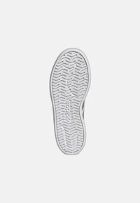 Witte rubberen zool met een getextureerd grip-patroon en ingeblazen logo. Licht verhoogde randen met een uniforme vorm, ontworpen voor stabiliteit.