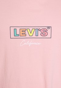 T-shirt rose clair avec le logo "LEVI'S" dans un rectangle multicolore et "California" en texte cursif blanc en dessous. Tissu en coton doux.