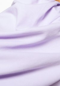 Tela de color púrpura claro con una textura suave, que muestra pliegues y caídas sutiles, indicando un diseño fluido y suave.