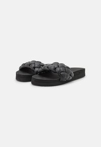 Black woven slide sandals feature a flat sole, padded straps, and a smooth texture, designed for comfort and casual wear.