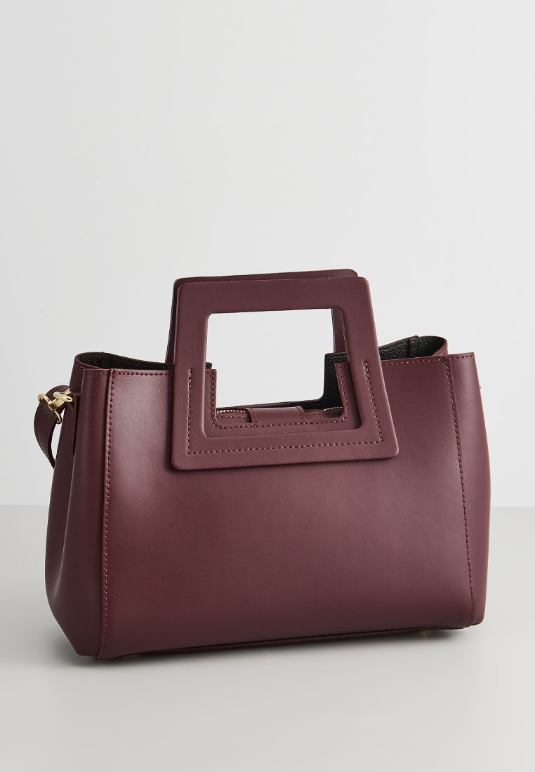 Sac à main en cuir bordeaux avec une anse à découpe carrée, forme structurée, texture lisse et accents en matériel doré.
