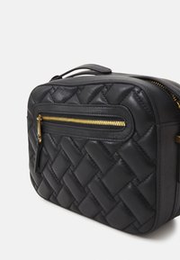 Borsa in pelle nera con texture intrecciata, dettaglio della cerniera dorata e manico corto. Presenta una tasca frontale con cerniera liscia. Forma rettangolare.