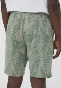 Pantaloni verdi con motivo di foglie, tessuto leggero, cintura elastica e tasche laterali. Adatti per un abbigliamento casual.