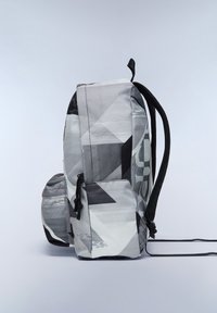 Zwart-witte geometrische rugzak met textuurstof, voorzien van schuine patronen, dubbele schouderbanden en een voorvak met een trekkoordsluiting.
