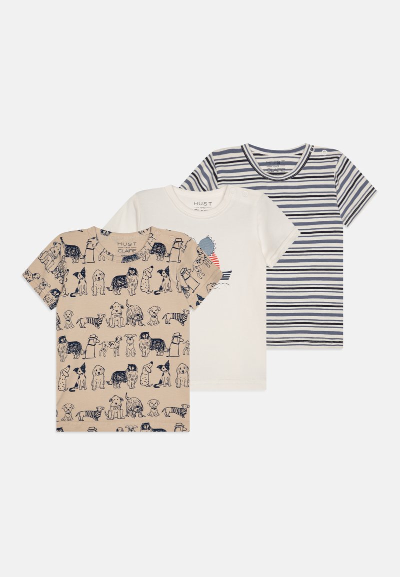 Três camisas de manga curta: uma bege com estampas de cães, uma branca com um gráfico e uma com riscas azul-marinho. Todas apresentam um material de algodão macio.