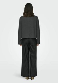 Szary, krótki żakiet wykonany z teksturowanej tkaniny, w połączeniu z czarnymi spodniami o szerokich nogawkach. Elegancki design z minimalnymi detalami.