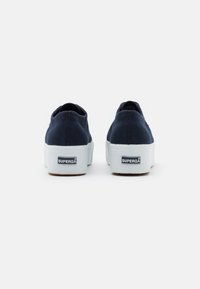 Sneakers in tela blu con suole in gomma bianca, caratterizzati da una punta rotonda e cuciture di rinforzo; etichetta con marchio sul tallone.