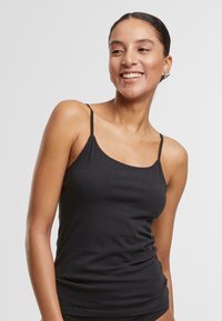 Black camisole top with thin straps, made from soft, stretchy fabric; fitted design with smooth texture and minimal seams.