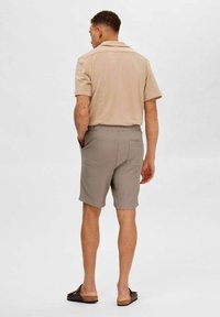 Polo shirt beige à manches courtes avec un col, associé à un short texturé gris clair doté d'une taille élastique et d'une poche arrière.