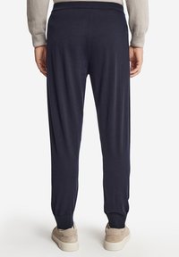 Navy joggingsbyxor med elastisk midja och muddar, med en avslappnad passform. Materialet verkar mjukt, lämpligt för vardags- eller träningsbruk.