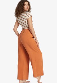 Striped short-sleeve top and orange wide-leg pants. The pants have a textured fabric and an elastic waistband.