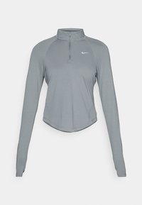 Grå langermet treningstopp med kvart-zip og tommelhull, med en liten hvit Nike-logo på venstre bryst.