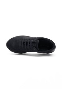 Zapatillas de ante negro con punta redondeada, diseño de cordones de cinco agujeros y superficie texturizada; estilo minimalista sin marca visible.