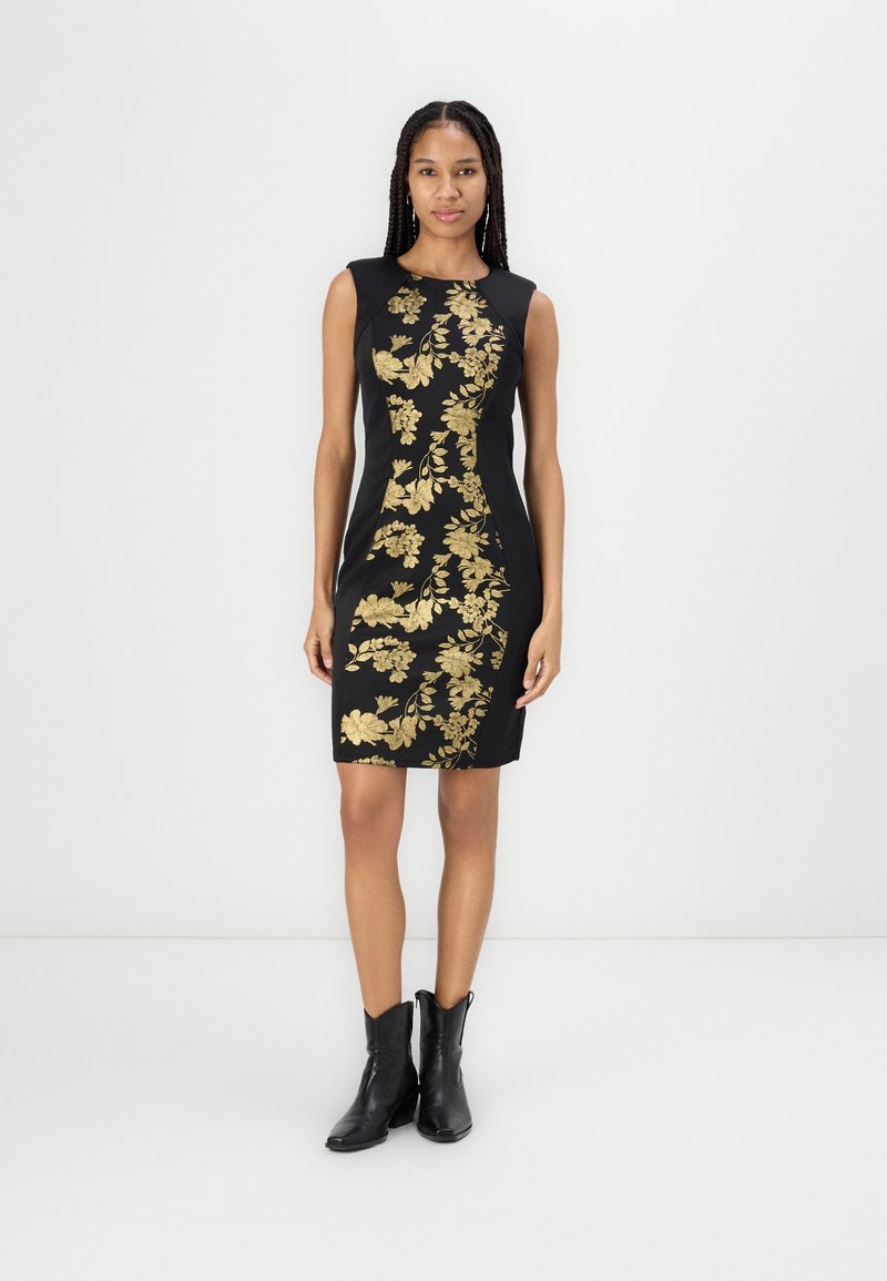 Rochie neagră ajustată cu broderie florală aurie, design fără mâneci și croială până la genunchi. Purtați cu botine negre.