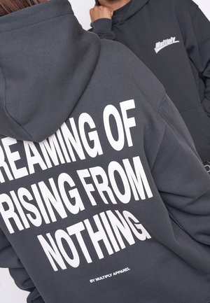 Dunkelgrauer Kapuzenpullover mit einer Fronttasche, der großen weißen Text zeigt: "VON NICHTS AUFSTEIGEN TRAUMEN" und "VON MULTIPLY APPAREL."