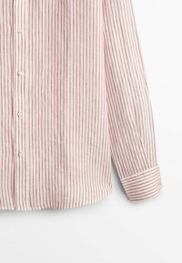 Chemise blanche à manches longues avec boutons, à fines rayures verticales rouges et manches retroussées, présentée sur un fond blanc uni.