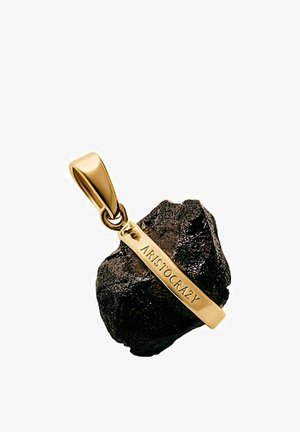 Asa de colgante en tono dorado unida a una piedra negra rugosa con una barra dorada grabada con la palabra "ARISTOCRAZY" en diagonal sobre la piedra.