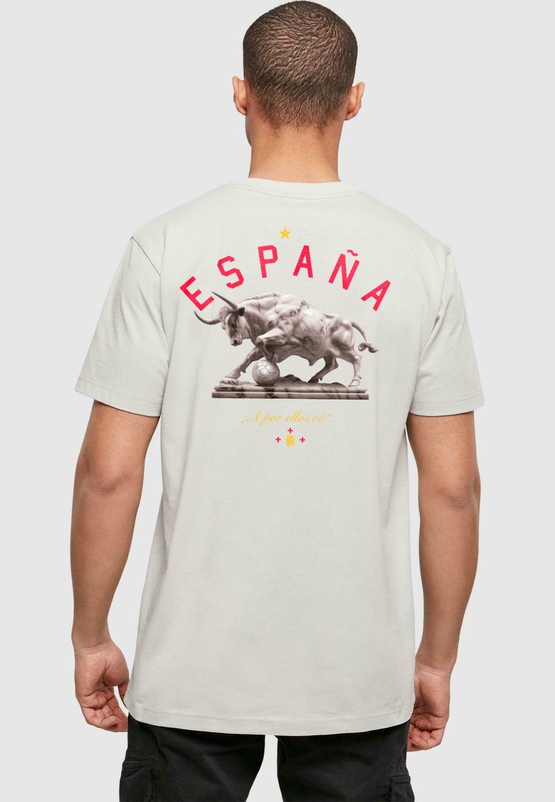 Világosszürke póló, hátán bika és focilabda grafikával, fölötte vastag piros betűkkel az "ESPAÑA" felirattal.