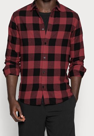 Camisa de cuadros roja y negra con cuello, mangas largas remangadas y botones negros, que presenta un dobladillo ligeramente curvado.