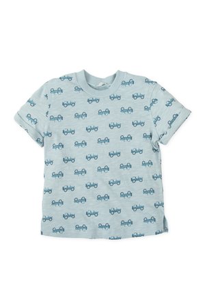 Camiseta de manga corta para niño pequeño de color azul claro con estampados de tractores azul oscuro por todo el tejido y mangas remangadas sobre un fondo blanco.