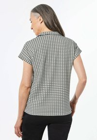 Kurzarm-Oberteil mit schwarz-weißem geometrischen Muster, ausgestattet mit einem kragenlosen Ausschnitt und einer lässigen Passform mit leichtem Fall und glatter Textur.