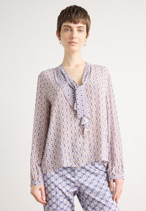 Lichtpaarse blouse met lange mouwen, voorzien van een gegolfde halslijn en een oogpatroon, gecombineerd met bijpassende getailleerde broeken met hetzelfde patroon.