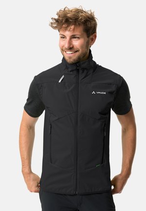Black sleeveless vest made from durable fabric. Features full zip, high collar, and two front zippered pockets. Logo on the chest.
