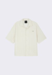 Chemise à manches courtes, boutonnée, en tissu texturé blanc cassé, avec un col à revers et un petit logo sur la poitrine gauche.