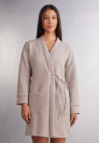 Beige texturovaný župan s chevronovým vzorem, s šálovým límcem, dlouhými rukávy, páskem v pase a bočními kapsami. Měkká látka s neformálním designem.