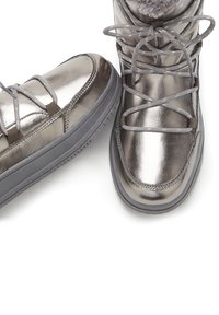 Metallische silberne Stiefel mit einer glatten Oberfläche, grauen Schnürsenkeln und einer dicken grauen Gummisohle. Mit einem Kunstfell-Akzent am oberen Rand.