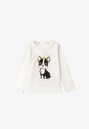 White long-sleeve shirt featuring a black and gold dog illustration with embellishments. Soft fabric with a ruffled neckline and printed accents.