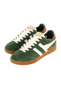 Zapatillas de ante verde con rayas y cordones blancos. Suela de goma. Lengüeta beige y detalle de marca. Punta redondeada y diseño de perfil bajo.