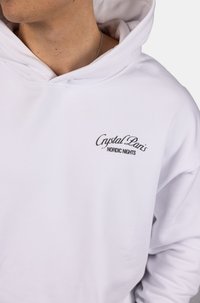 Felpa bianca in cotone con tasca frontale e un logo ricamato che recita "Crystal Paris" con "NORDIC NIGHTS" sottostante.