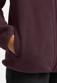 Veste en polaire bourgogne avec une surface texturée, fermeture éclair et poches latérales. Dispose de poignets élastiques pour le confort et un ajustement optimal.