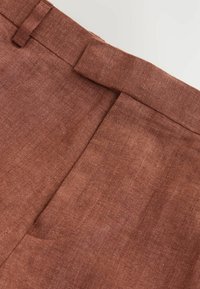 Pantalons en lin marron avec un devant plat, des passants de ceinture, et une texture subtile. Présente un design élégant adapté à un usage décontracté ou semi-formel.