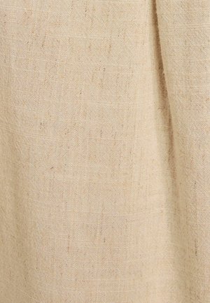 Beige linen fabric with visible weave texture and natural irregularities, showing slight folds and soft shadows.