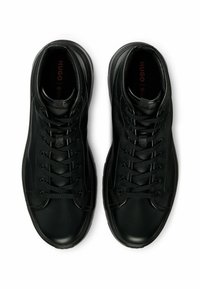 Schwarze Ledersneaker mit strukturiertem Obermaterial, runder Spitze und kontrastierenden glatten Akzenten. Ausgestattet mit schwarzen Schnürsenkeln und Logo auf der Innensohle.