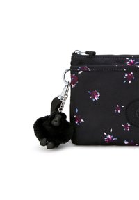 Custodia in nylon nera con motivo floreale in viola e bianco. Presenta un logo rotondo e un portachiavi a forma di gorilla nero attaccato. Chiusura con zip nella parte superiore.