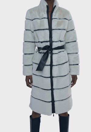 Cappotto caldo di lunghezza media, con zip, in morbido bianco con strisce nere. Caratterizzato da un colletto alto e una cintura in satin nera in vita.