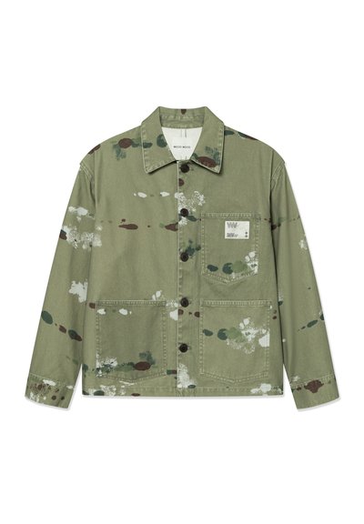 Chaqueta de lienzo en verde apagado con manchas de pintura de colores. Cuenta con cierre frontal de botones, dos bolsillos de parche y una etiqueta en el pecho.
