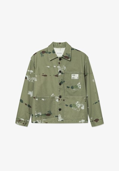 Veste en toile de couleur vert discret avec des éclaboussures de peinture multicolores. Dotée d'une fermeture à boutons à l'avant, de deux poches plaquées et d'une étiquette sur la poitrine.