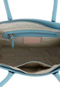 Jasnoniebieska skórzana torebka na zamek błyskawiczny, beżowe wnętrze, wewnętrzna kieszeń na zamek oraz mała różowa metka.