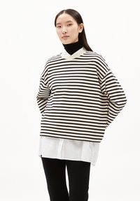 Top a maniche lunghe a righe bianche e nere con scollatura rotonda, vestibilità comoda e camicia bianca sovrapposta sotto. Tessuto morbido, design informale.
