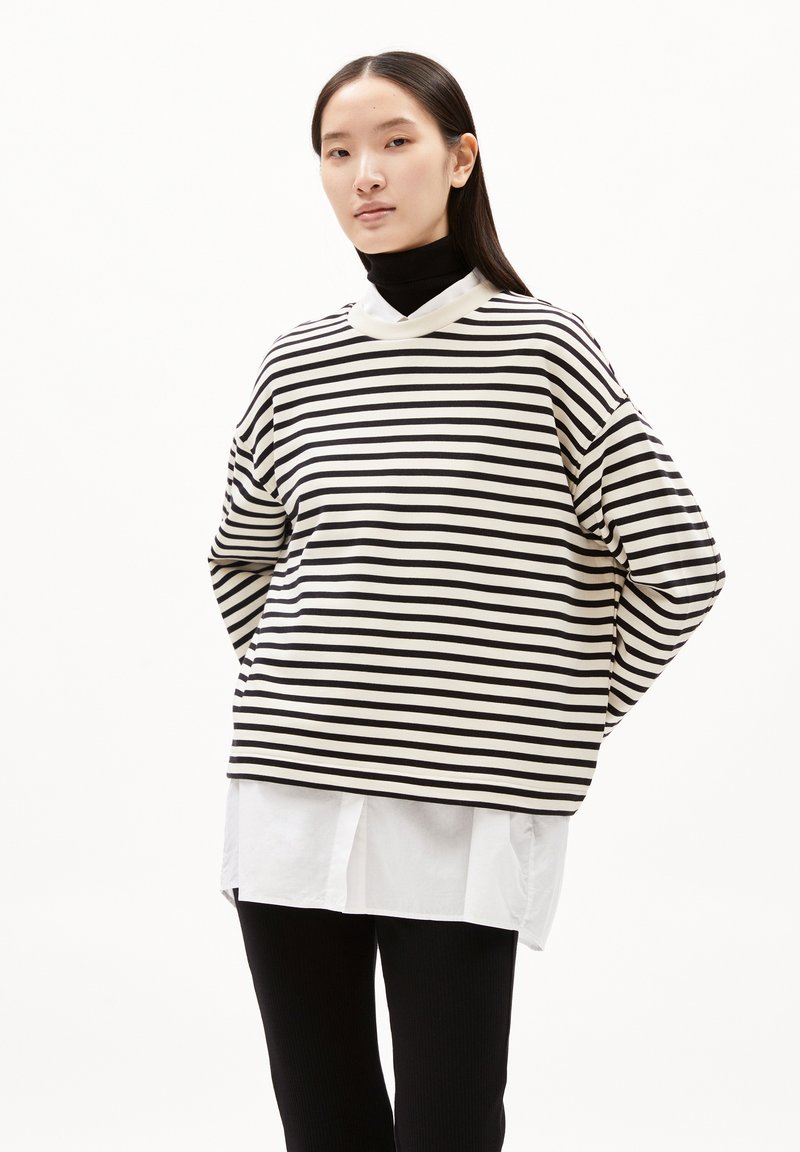 Top a maniche lunghe a righe bianche e nere con scollatura rotonda, vestibilità comoda e camicia bianca sovrapposta sotto. Tessuto morbido, design informale.