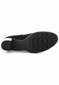 Chaussure en daim noir avec un bout arrondi, un large talon bas et une semelle en caoutchouc arborant un motif en zigzag pour plus d'adhérence. Le logo de la marque est embossé sur la semelle.